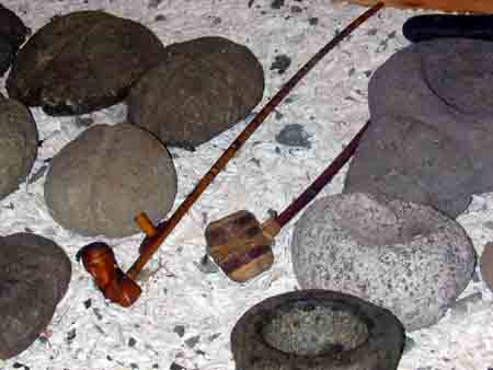 A gauche: pierres de lest pour filets de p&ecirc;che; A droite bols divers.Les objets en bois sont des pipes de Paix.