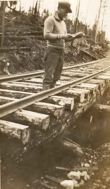 Leo Harris debout sur la voie ferrée. Les rails reposent sur des traverses taillées à la main.